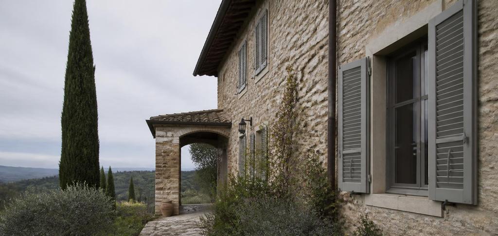 Toskanisches Landhaus aus Naturstein mit Fensterläden, Zypresse und Blick über die Hügel